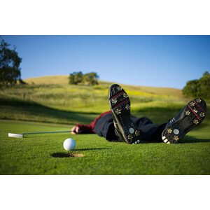 Fotografie Golfer lying on green, ball on edge of hole, Joe McBride, 40 × 26.7 cm
